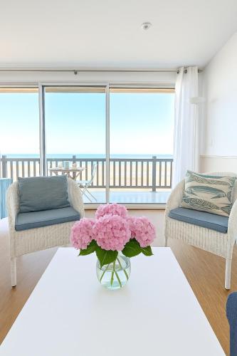 un salon avec un canapé et une table avec des fleurs dans l'établissement L Horizon, F3, vue mer exceptionnelle, 3 ou 4 pers, à Blonville-sur-Mer