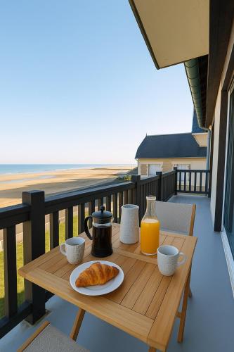 - une table en bois avec du café et des croissants sur un balcon dans l'établissement L Horizon, F3, vue mer exceptionnelle, 3 ou 4 pers, à Blonville-sur-Mer