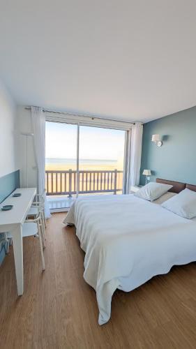 une chambre avec un grand lit blanc et un bureau dans l'établissement L Horizon, F3, vue mer exceptionnelle, 3 ou 4 pers, à Blonville-sur-Mer