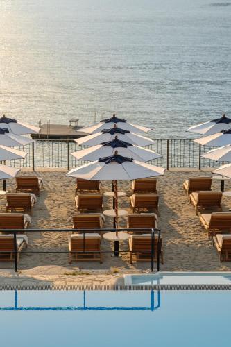 a group of beach chairs and umbrellas next to the ocean at Grand Hotel Villa Serbelloni - A Legendary Hotel in Bellagio