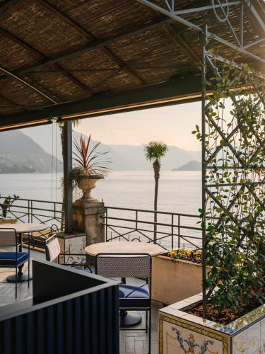 a patio with tables and chairs and a view of the water at Grand Hotel Villa Serbelloni - A Legendary Hotel in Bellagio