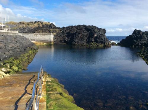 a body of water with rocks and the ocean at Whalesbay Hotel Apartamentos in Capelas