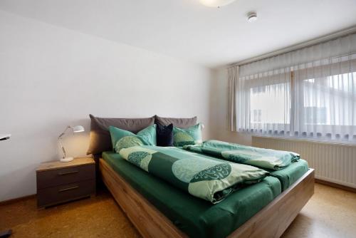 Un dormitorio con una cama con sábanas verdes y una ventana. en Ferienhaus Hilde, en Schwangau
