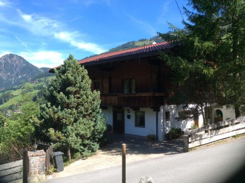a house with a tree next to a road at Beautiful Family Chalet in the heart of Inneralpbach in Inneralpbach