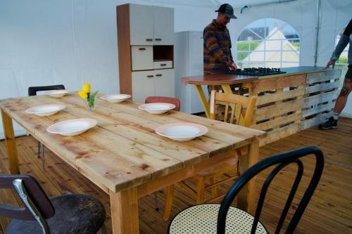 - une table en bois dans une cuisine avec un homme préparant la nourriture dans l'établissement Glamping Spot - Penmarch, à Penmarcʼh
