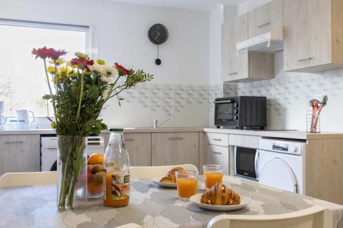 - une cuisine avec une table, un vase de fleurs et du jus d'orange dans l'établissement L'Ilot Narossais 10 - idéal curiste - clim - proche Dax, à Narrosse