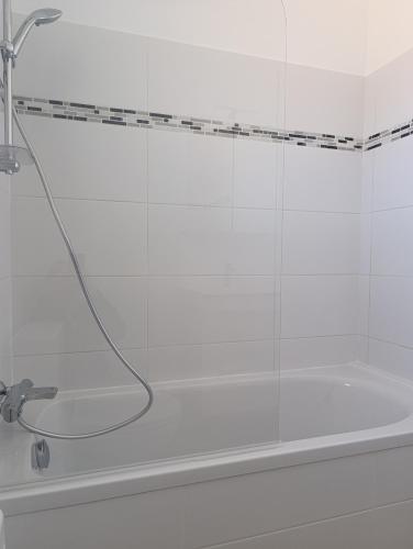 La salle de bains est pourvue d'une baignoire et d'une douche. dans l'établissement Maison centre de Barfleur, à Barfleur