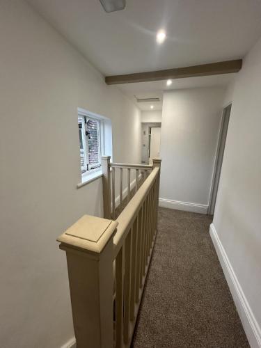 a hallway with a stairway with a wooden railing at Ironbridge town apartment in Ironbridge