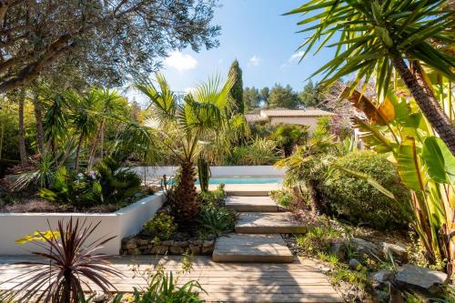 un jardin avec des palmiers et une passerelle dans l'établissement Villa Nouméa, à Cases-de-Pène