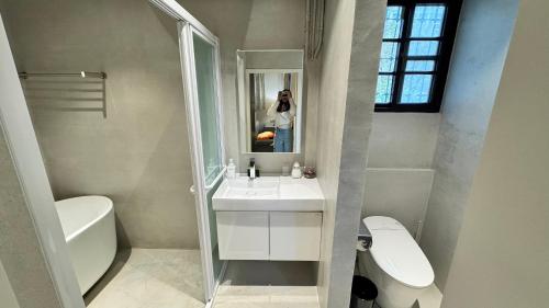 a woman taking a picture of a bathroom with a sink at 眷村1954 Guest House in Taipei