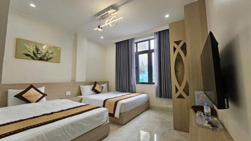 a hotel room with two beds and a window at Lucky Hotel Uông Bí in Uông Bí