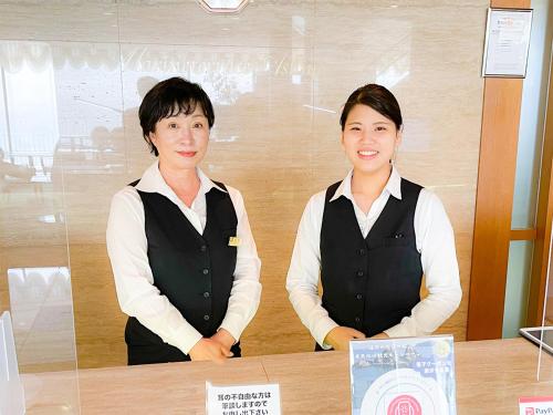 two women are standing at a table in a room at Kokumin Shukusha Marine Terrace Ashiya in Kitakyushu