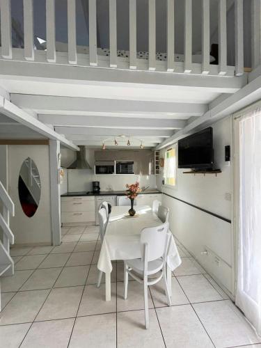 une salle à manger blanche avec une table et des chaises dans l'établissement Maison Cosy Clim Jardin Proche Océan, à Lacanau