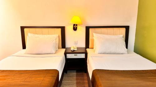 two beds sitting next to each other in a room at Hotel Seri Malaysia Kepala Batas in Kepala Batas