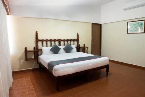a bedroom with a bed with white sheets and blue pillows at Collection O Hotel Mocambo, Boca del Río in Veracruz