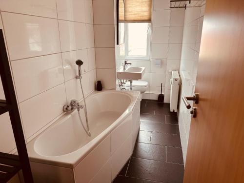 a white bathroom with a tub and a toilet at Aufladen & Entspannen im Senfzimmer mit Balkon in Gerwisch