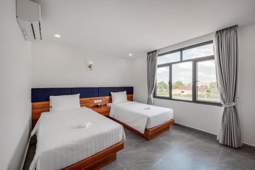 a hotel room with two beds and a window at Soho Villa & Resort in Phumĭ Stœ̆ng Vêng