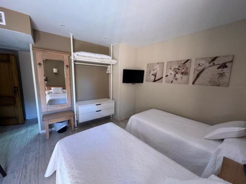 a hotel room with two beds and a mirror at Hotel Alda A Boira in Jaca