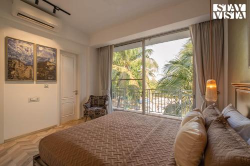 a bedroom with a large bed and a balcony at StayVista at Casa Vida Zeo with BBQ, Pool, WiFi in Assagao