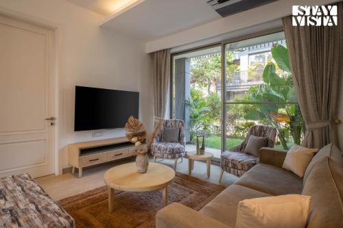 a living room with a couch and a tv at StayVista at Casa Vida Zeo with BBQ, Pool, WiFi in Assagao