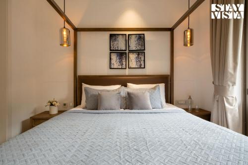 a bedroom with a bed with white sheets and pillows at StayVista at Casa Vida Zeo with BBQ, Pool, WiFi in Assagao