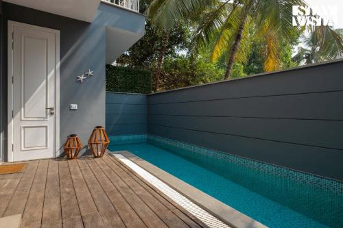 a swimming pool in a house with a blue wall at StayVista at Casa Vida Zeo with BBQ, Pool, WiFi in Assagao