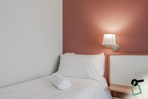 a bed with a white pillow and a light on a wall at HOTIDAY Room Collection - Celle Ligure in Celle Ligure