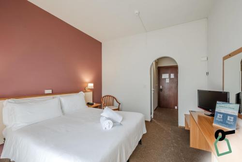 a bedroom with a large white bed and a television at HOTIDAY Room Collection - Celle Ligure in Celle Ligure