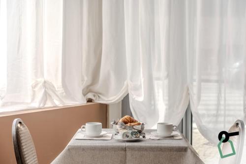 a table with two cups and a bowl of food at HOTIDAY Room Collection - Celle Ligure in Celle Ligure