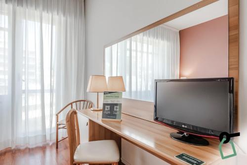 a room with a television on a wooden desk at HOTIDAY Room Collection - Celle Ligure in Celle Ligure
