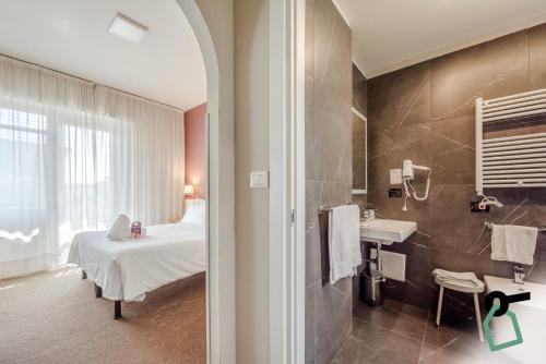 a bathroom with a bed and a sink in a room at HOTIDAY Room Collection - Celle Ligure in Celle Ligure