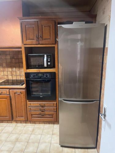 une cuisine avec un réfrigérateur en acier inoxydable et un micro-ondes dans l'établissement Maison à 13 minutes de la plage, à Saleilles