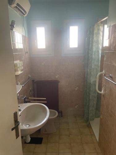 La salle de bains est pourvue d'un lavabo, de toilettes et de 2 fenêtres. dans l'établissement Maison à 13 minutes de la plage, à Saleilles