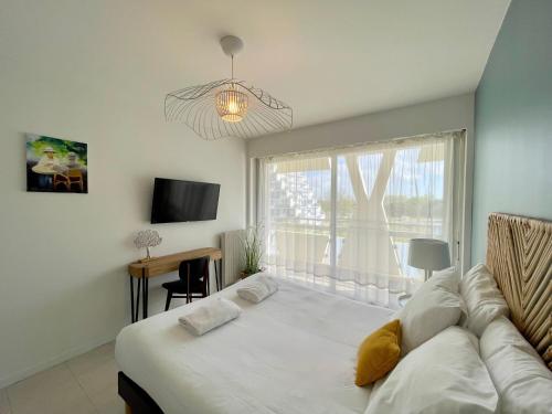 une chambre avec un grand lit blanc avec une fenêtre dans l'établissement PGH N31- Plage à 50m, Centre-Ville, Parking Privé, à La Grande Motte