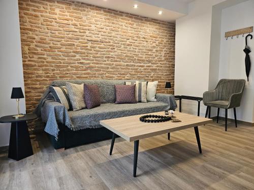 a living room with a couch and a brick wall at Silk Suites by YHA in Athens