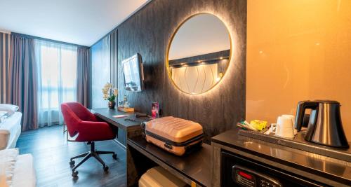 a hotel room with a desk and a mirror at PLAZA Premium Parkhotel Neu-Ulm in Ulm