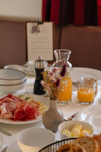 a table with plates of food and a bottle of orange juice at Panorama Hotel Flora in Villandro