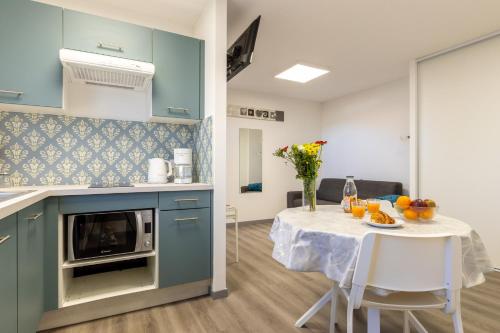 une cuisine avec des placards bleus et une table avec des fruits. dans l'établissement L'Ilot Narossais 5 - idéal curiste - clim - proche Dax, à Narrosse