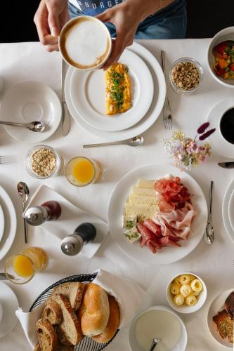 a table with plates of food and a cup of coffee at Panorama Hotel Flora in Villandro