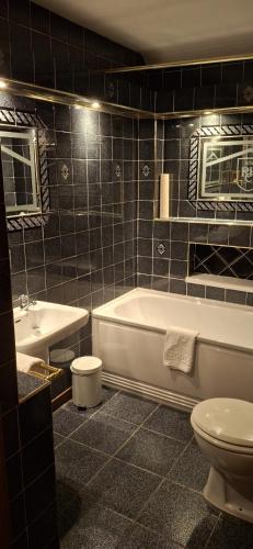a bathroom with a tub and a toilet and a sink at Royal Court Hotel in Portrush