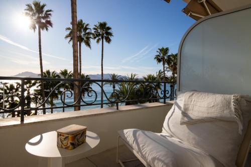 - un balcon avec un lit, une table et des palmiers dans l'établissement Modern 1-bedroom apartment with sea view on La Croisette, à Cannes