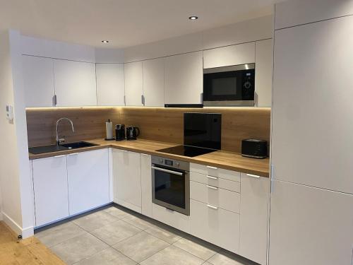 une cuisine avec des armoires blanches, un évier et un micro-ondes dans l'établissement Au toit de la cathédrale, à Sens