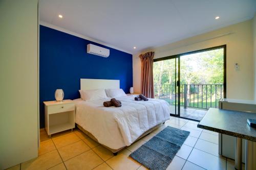 a bedroom with a large bed with a blue wall at Mshengu Kruger Lodge in Marloth Park