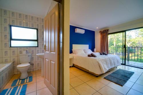 a bedroom with a bed and a bathroom with a tub at Mshengu Kruger Lodge in Marloth Park