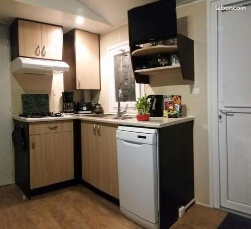 La cuisine est équipée de placards bruns et d'un lave-vaisselle blanc. dans l'établissement MH 387 3 chambres 1 salle de bain dans camping 4 étoiles, à Saint-Julien-en-Born
