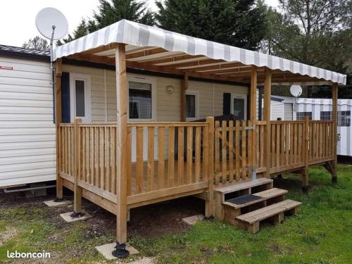 une maison avec une terrasse en bois et un toit dans l'établissement MH 387 3 chambres 1 salle de bain dans camping 4 étoiles, à Saint-Julien-en-Born