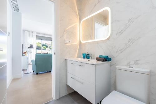 a white bathroom with a sink and a mirror at Apartamento bajo luxury golf Baviera Hills 54 in Caleta De Velez