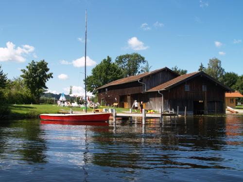 a red boat on the water next to a barn at Eichenhof in Waging am See