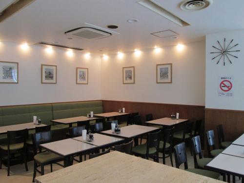 a dining room with tables and chairs and a clock on the wall at Shin-Osaka Sunny Stone Hotel in Osaka