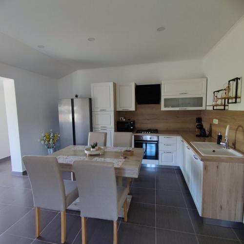 a kitchen with a wooden table and white cabinets at Apartman Đokić 3 in Bale